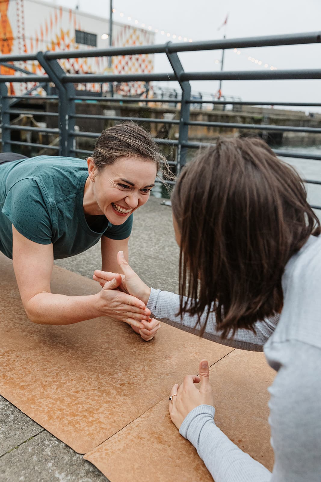 Briana and Jess face to face and smiling, each holding a plank position.