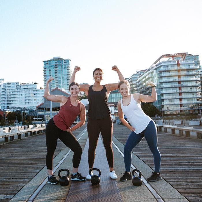 Andrea, Jess, and Briana flexing with kettlebells.